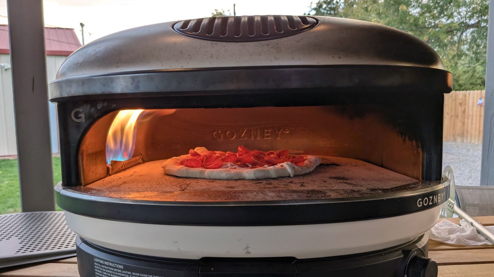 A pepperoni pizza baking inside the Gozney Arc XL under a rolling yellow flame.
