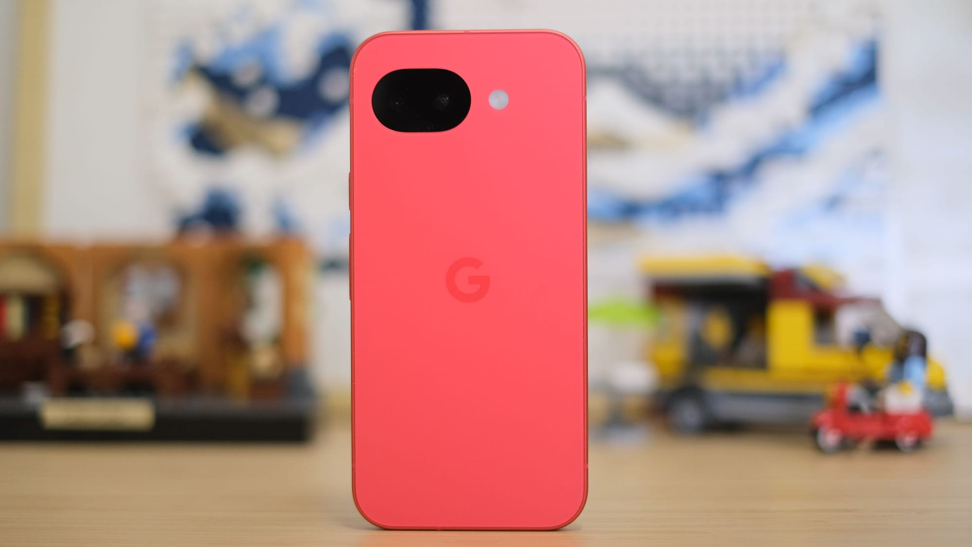 The back of the same coral smartphone, featuring a centered "G" logo. At the top, there is a unique black, pill-shaped horizontal camera bar containing two lenses and an adjacent LED flash.