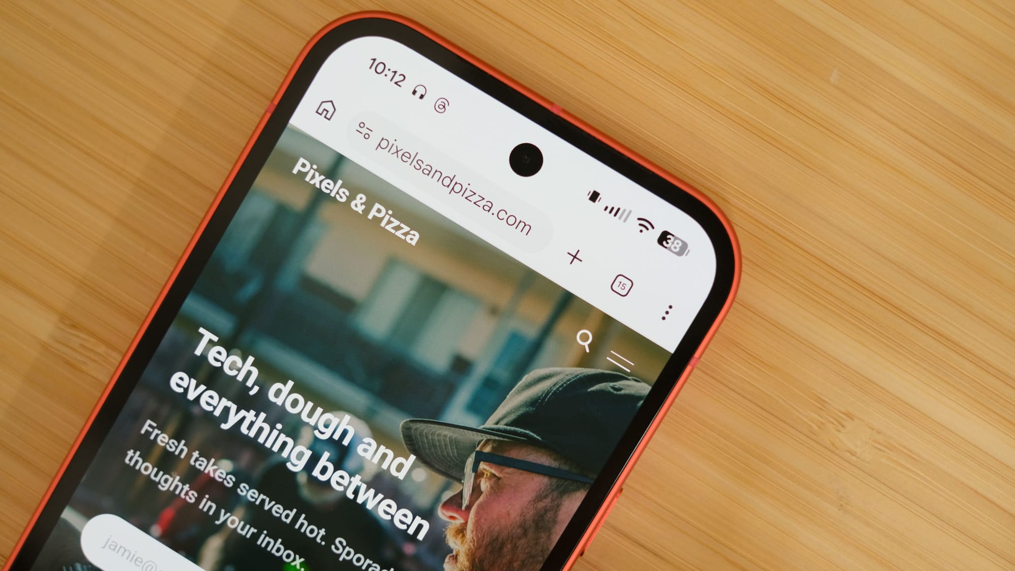 A tight close-up of the top portion of the smartphone screen. It shows a mobile web browser open to "pixelsandpizza.com" with a header that reads "Tech, dough and everything between" over a photo of a man in a hat.